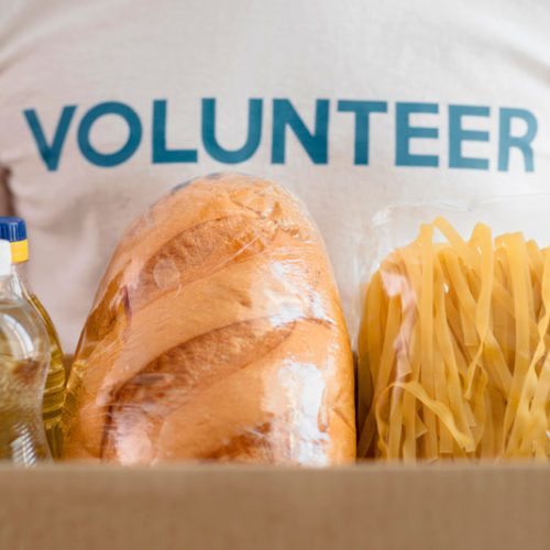 male-volunteer-holding-box-with-provisions-charity